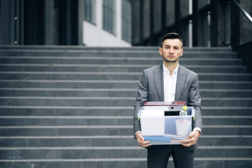 man standing on steps with box of stuff after losing job